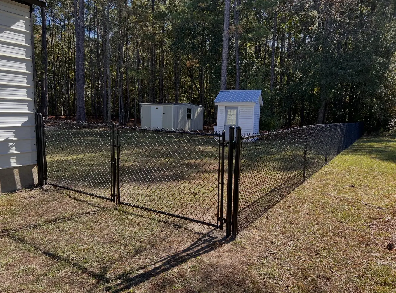 Black-coated residential chain-link fence with a matching double gate around a backyard