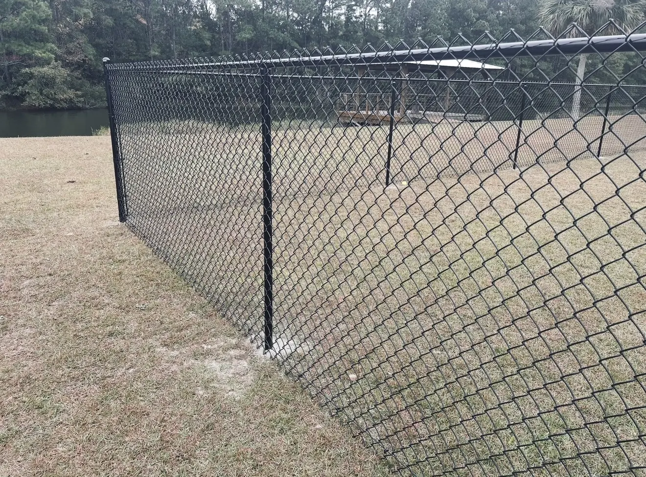 Close view of a black-coated residential chain-link fence corner and top rail