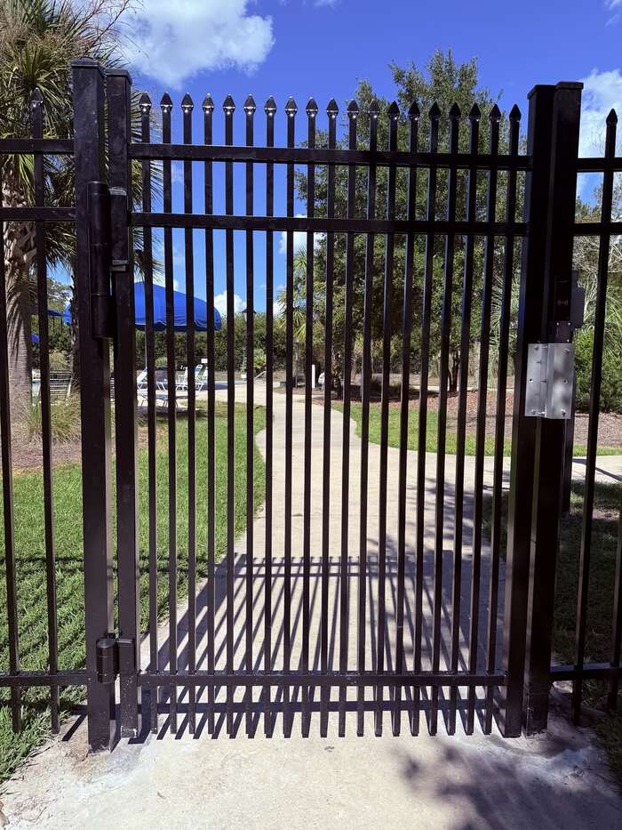 Black aluminum controlled-access pedestrian gate at the Buckhead East community pool