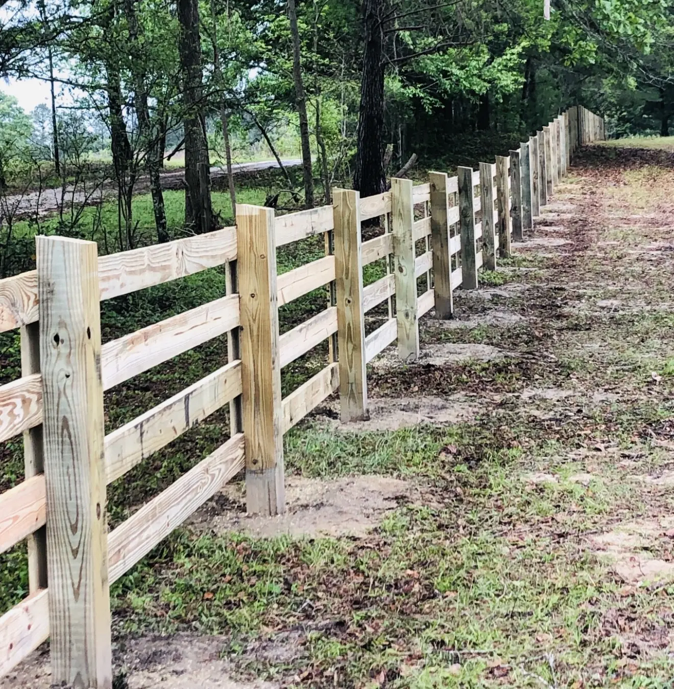 Four-board wood farm fence following uneven ground