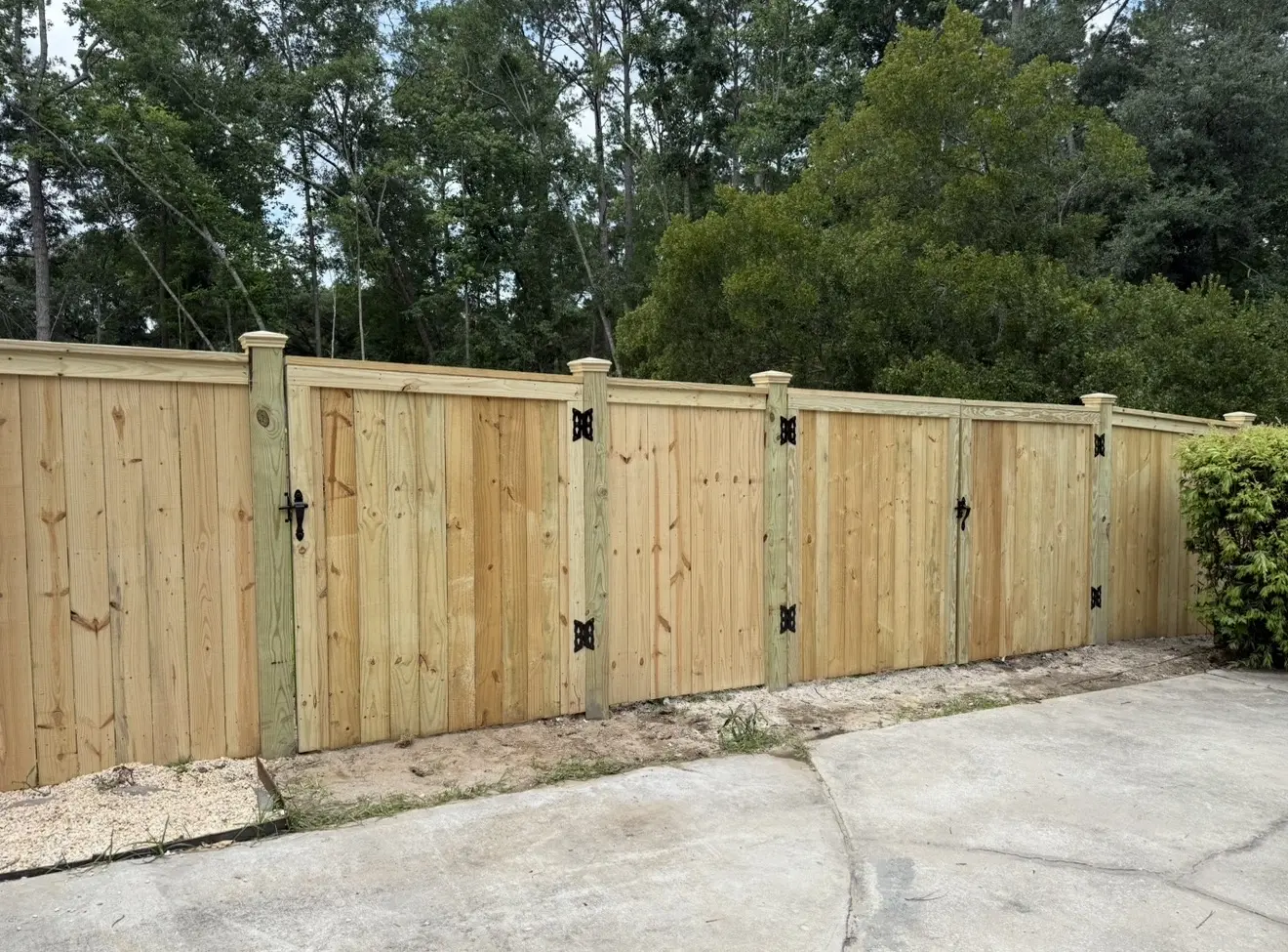 Pressure-treated cap-and-trim privacy fence with matching double driveway gates