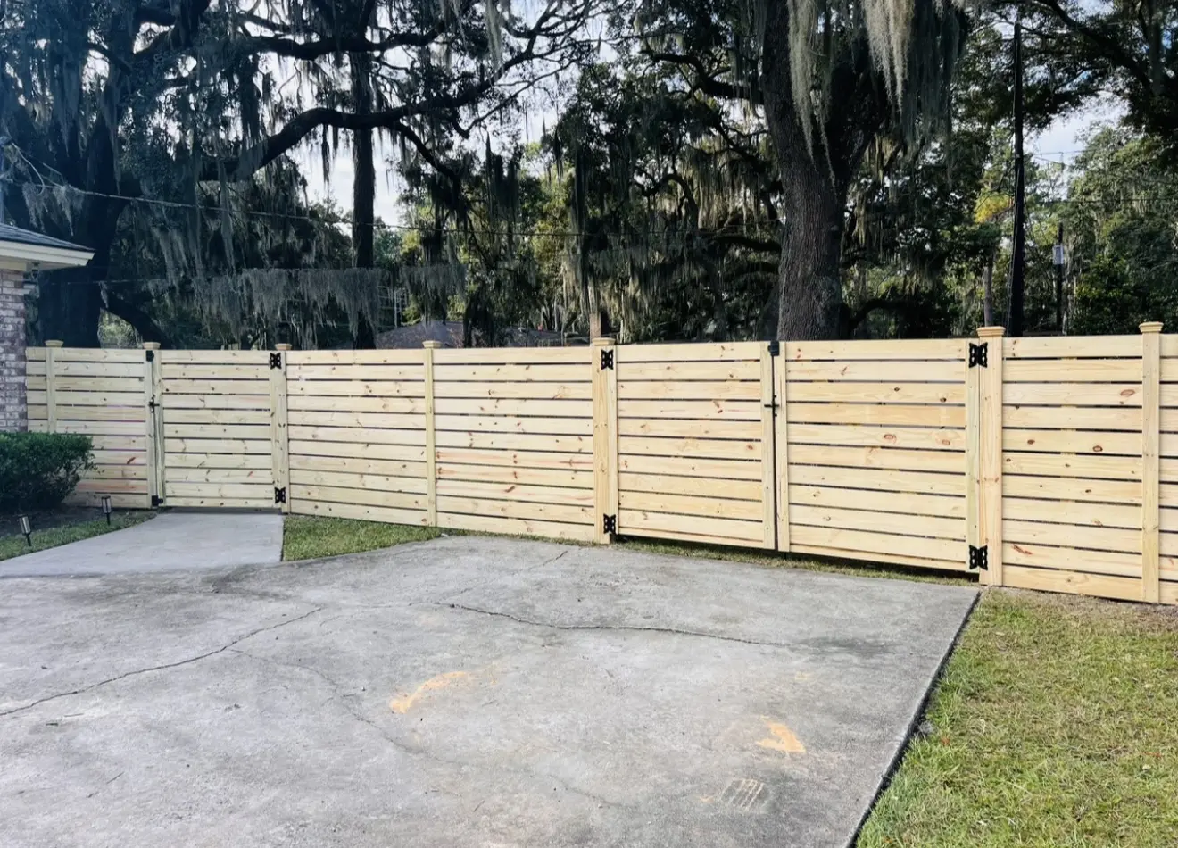 Horizontal pressure-treated wood privacy fence with matching double driveway gates