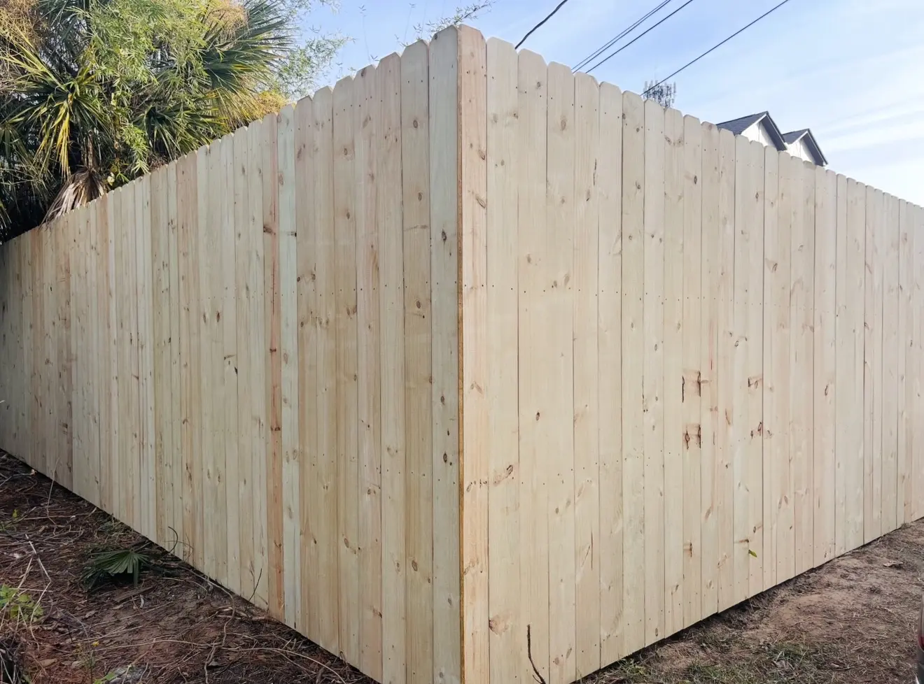 Solid pressure-treated stockade privacy fence meeting at a residential property corner